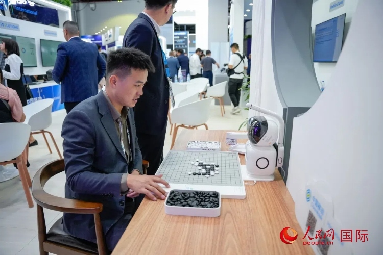 觀眾在中國(guó)移動(dòng)國(guó)際有限公司展臺(tái)體驗(yàn)智慧圍棋機(jī)器人。人民網(wǎng) 塔里克·易卜拉欣攝