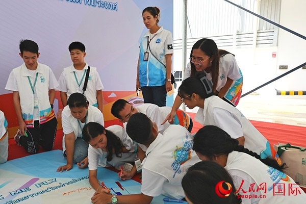 泰國學(xué)生在開營儀式展板上繪制圖案。人民網(wǎng)記者 白元琪攝