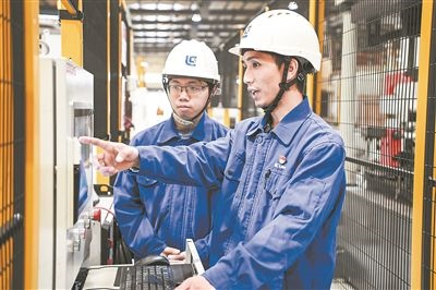 在廣西柳工機(jī)械股份有限公司生產(chǎn)車間內(nèi)，一名高級(jí)技師（右）給徒弟講解數(shù)控設(shè)備操作細(xì)節(jié)。新華社記者 曹祎銘攝