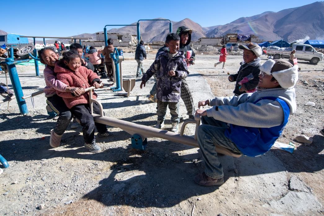 1月11日，在定日縣措果鄉(xiāng)塘仁村安置點，西藏星光社會工作服務(wù)中心志愿者和孩子們一起玩耍，進行災(zāi)后心理疏導(dǎo)。人民網(wǎng)記者 翁奇羽攝
