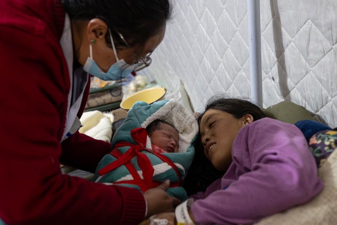 1月10日，定日縣中心醫(yī)院的婦產(chǎn)科醫(yī)生悉心照看一位母親和她懷里的新生兒。人民日報記者張武軍攝