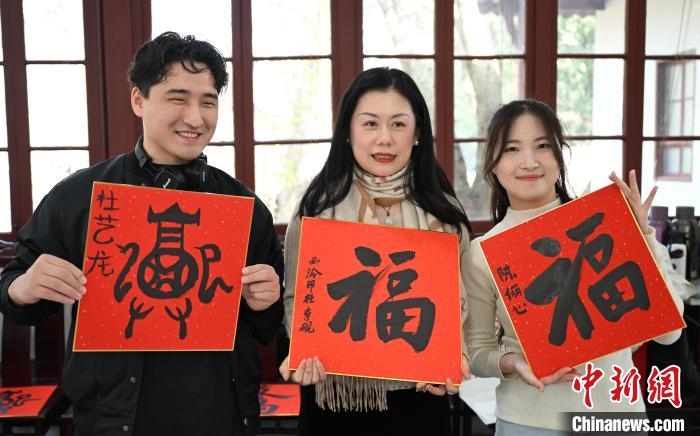 1月20日，外籍留學(xué)生和西泠印社社員李硯(中)展示各自創(chuàng)作的福貼。當(dāng)日，來自巴西、馬來西亞、加納、哈薩克斯坦的外籍留學(xué)生在浙江杭州西泠印社體驗福貼、春聯(lián)和篆刻，感受古老的中國傳統(tǒng)文化。中新社記者 王剛 攝