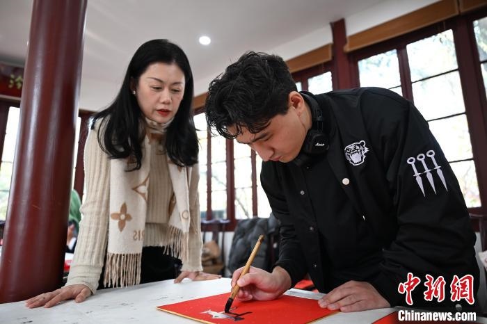 1月20日，外籍留學(xué)生在西泠印社社員李硯指導(dǎo)下寫福。當(dāng)日，來自巴西、馬來西亞、加納、哈薩克斯坦的外籍留學(xué)生在浙江杭州西泠印社體驗福貼、春聯(lián)和篆刻，感受古老的中國傳統(tǒng)文化。中新社記者 王剛 攝