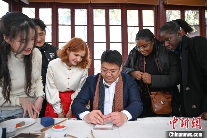 1月20日，篆刻家王臻向外籍留學(xué)生展示篆刻印章。當(dāng)日，來自巴西、馬來西亞、加納、哈薩克斯坦的外籍留學(xué)生在浙江杭州西泠印社體驗福貼、春聯(lián)和篆刻，感受古老的中國傳統(tǒng)文化。中新社記者 王剛 攝