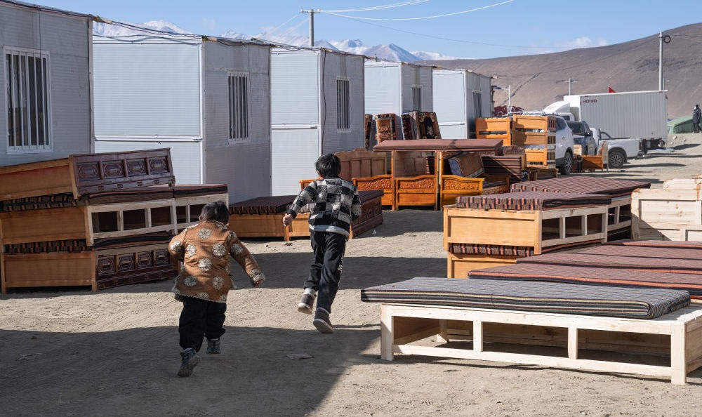 2025年1月13日，在定日縣嘎旦村，兩個(gè)孩子在剛運(yùn)來的兩排藏床間奔跑。新華社記者丁增尼達(dá) 攝