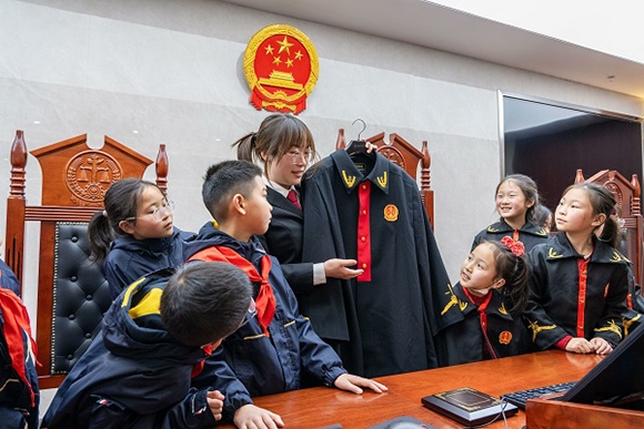 圖②：干警向同學(xué)們介紹法袍。