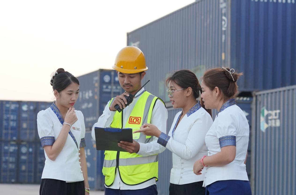 萬象南站貨運(yùn)值班員陳尼啦（左一）與同事在一起討論工作。老中鐵路有限公司供圖