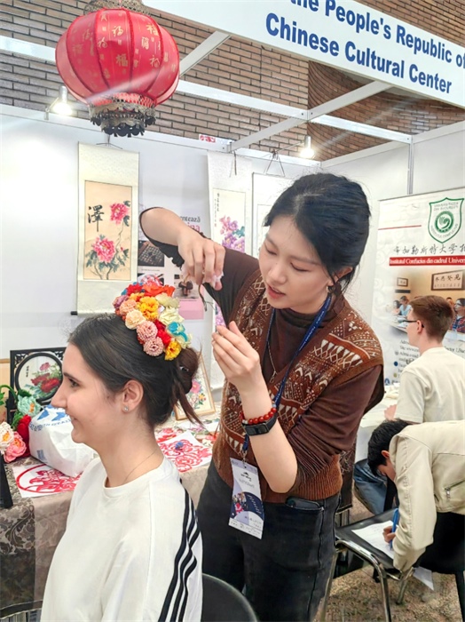 展覽正值羅馬尼亞迎春花節(jié)，國際中文教師志愿者潘婧穎向游客們介紹了國家非物質文化遺產——福建泉州的簪花文化。布加勒斯特大學孔子學院供圖。