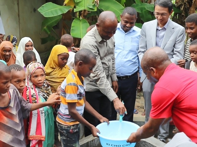 在日前舉行的安全供水工程揭牌儀式上，當(dāng)?shù)匦∨笥言诠┧c(diǎn)接水。 施亮攝