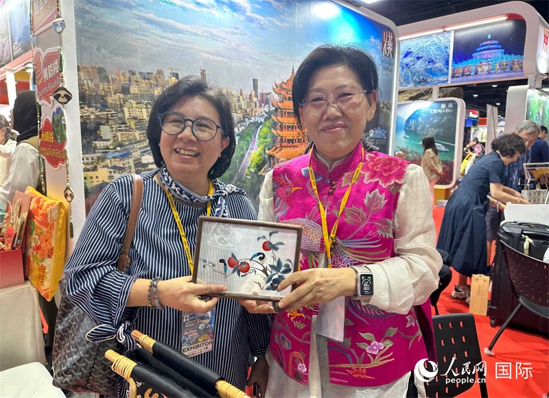 中國“大冶刺繡”傳承人劉小紅（右）參加泰國國際旅游展，向觀眾介紹中國非遺刺繡針法。人民網(wǎng)記者 簡承淵攝