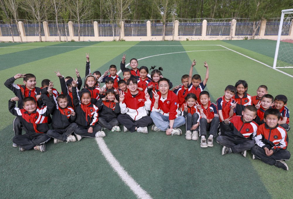 4月23日，在新疆克州阿圖什市哈拉峻鄉(xiāng)謝依特小學(xué)，支教教師王俊文（中左）、李軻凡（中右）和學(xué)生在一起。