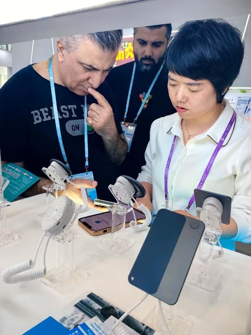 展臺(tái)工作人員向外商展示“AI TOP翻譯終端”。圖片來(lái)源：受訪者提供