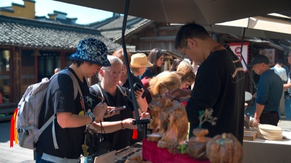 “五一”期間，游客正在烏鎮(zhèn)“水鄉(xiāng)碼頭”挑選購買文創(chuàng)產(chǎn)品。受訪者供圖