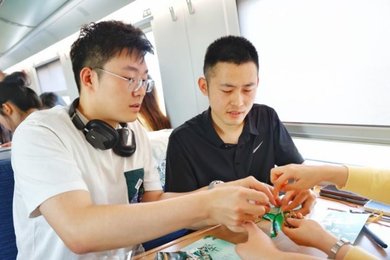 G232次旅客親手制作端午荷包和五彩繩。王磊攝